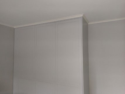 platsbyggd grå garderob med ramdörrar måttanpassad mot väggar och tak